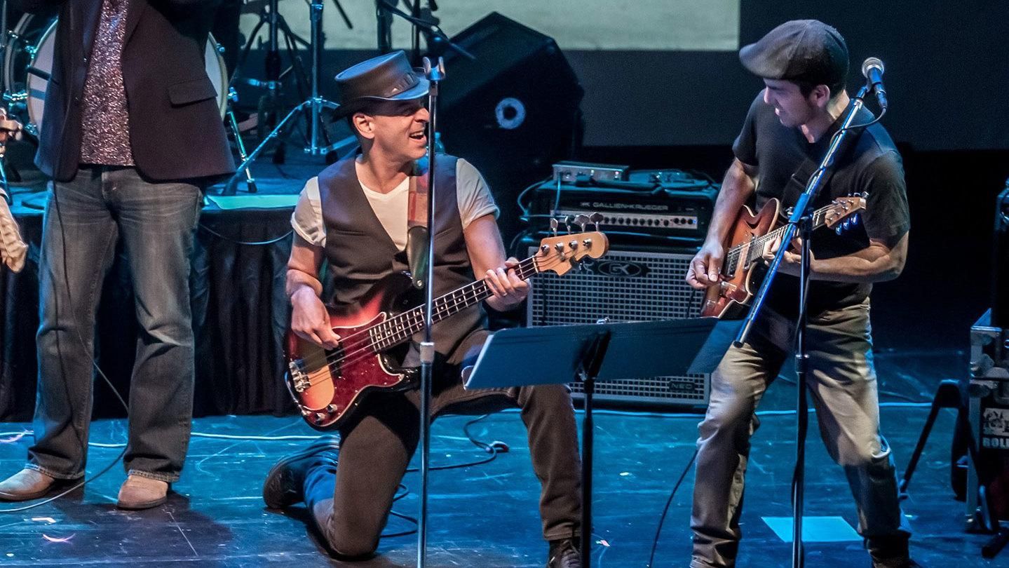 A group of men are playing guitars and singing on a stage.