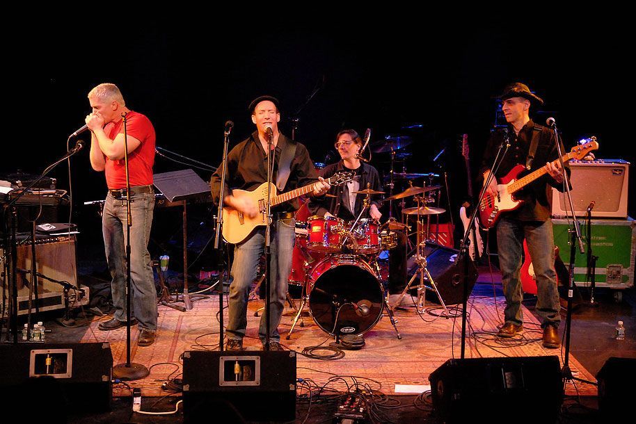 A group of men are playing guitars and singing on a stage.