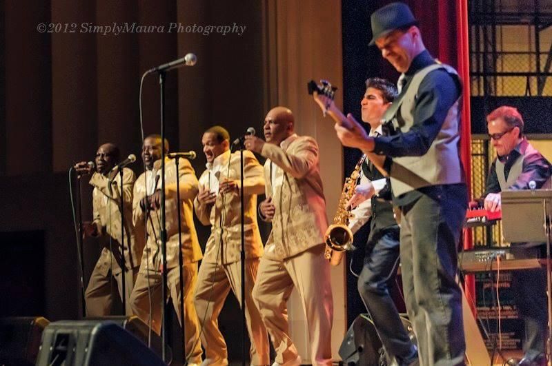 A group of men singing and playing instruments on a stage