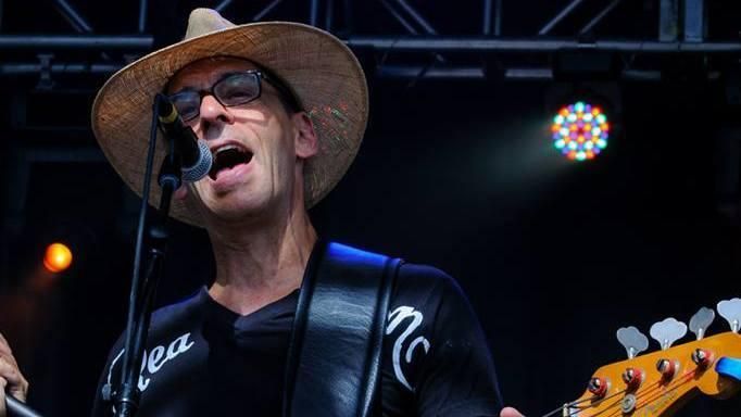 A man in a cowboy hat is singing into a microphone while playing a guitar.