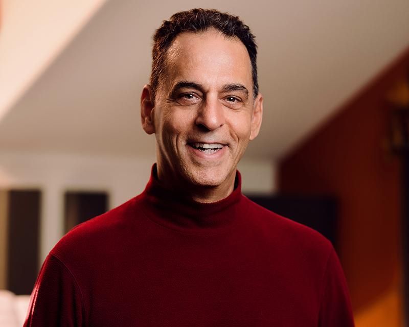 A man in a red turtleneck is smiling for the camera.