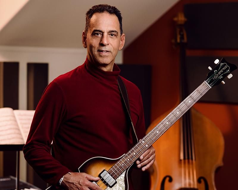 A man in a red sweater is holding a guitar