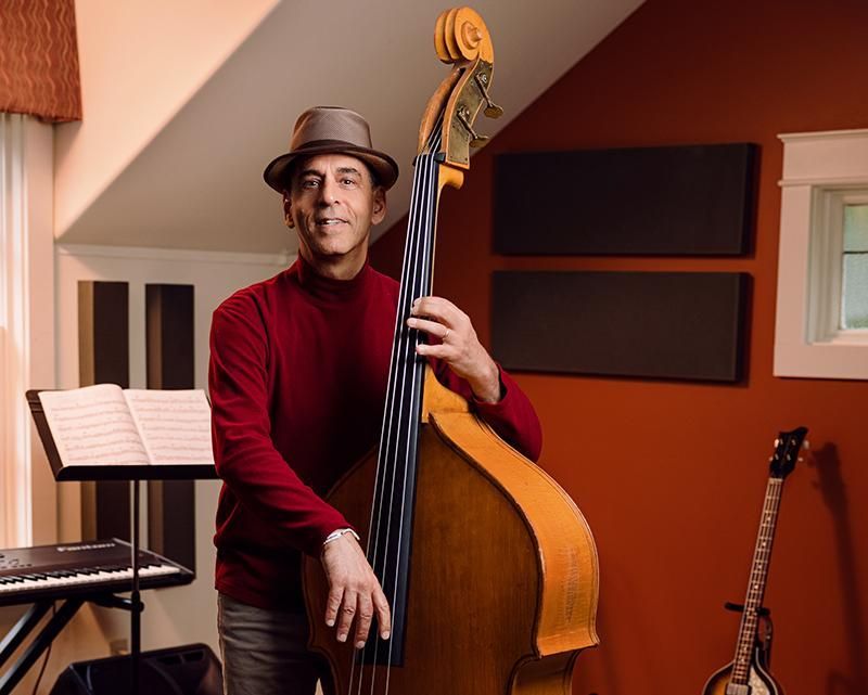 A man in a hat is holding a double bass