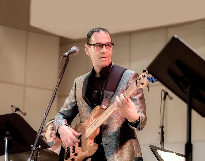 A man in a suit is playing a guitar and singing into a microphone.