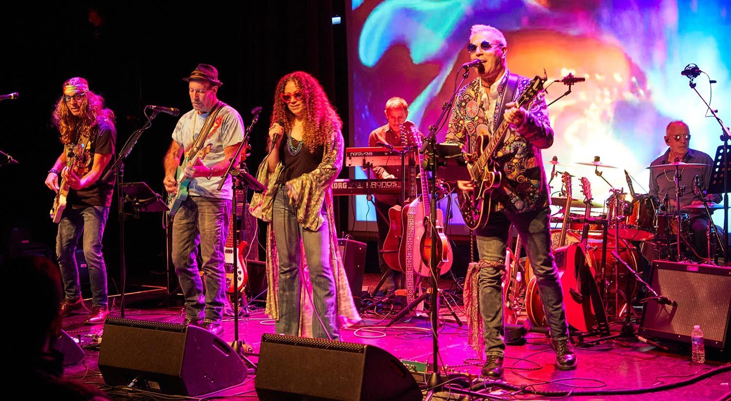 A group of men are playing guitars and drums on a stage.