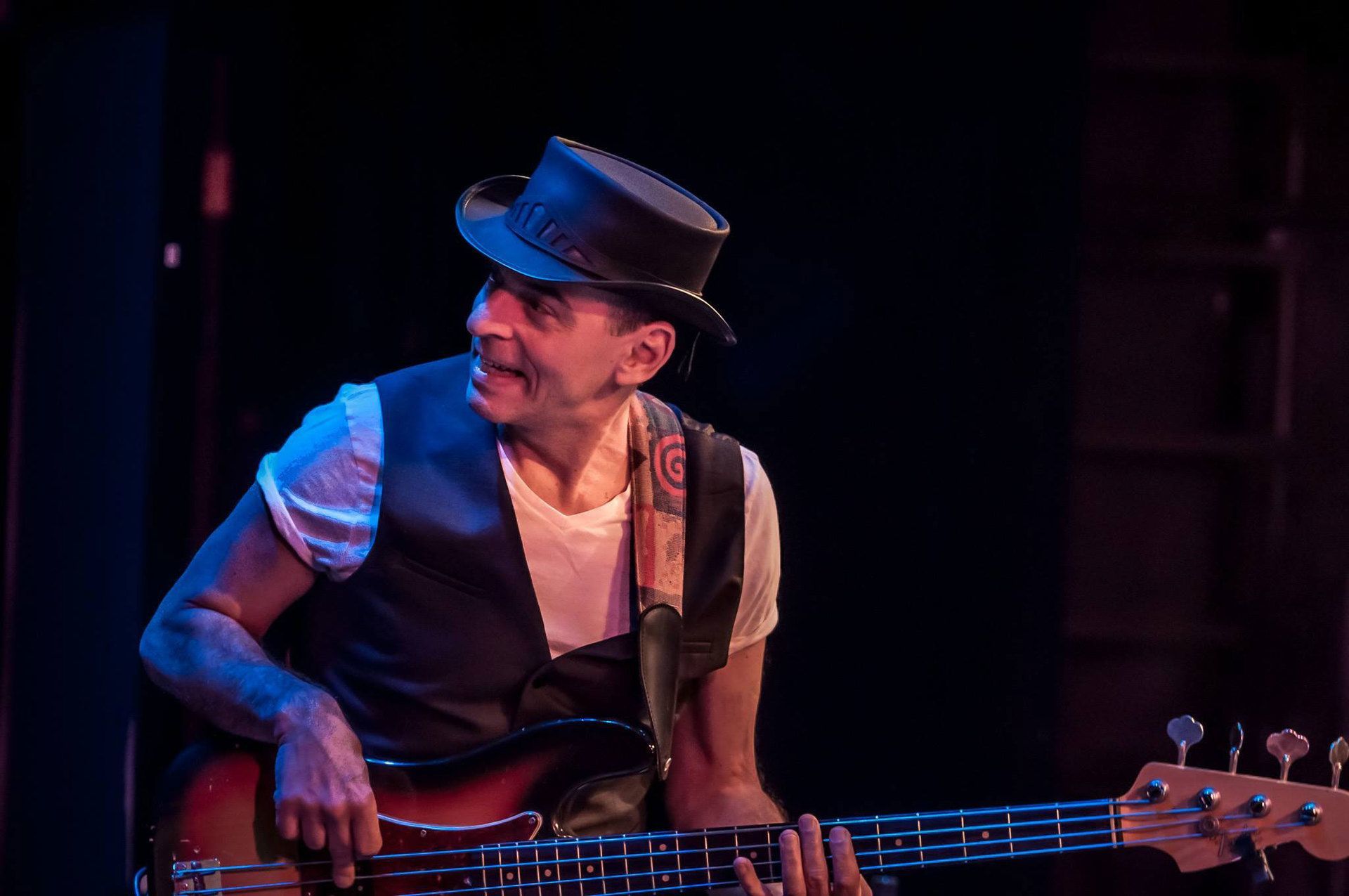 A man in a top hat is playing a bass guitar on a stage.