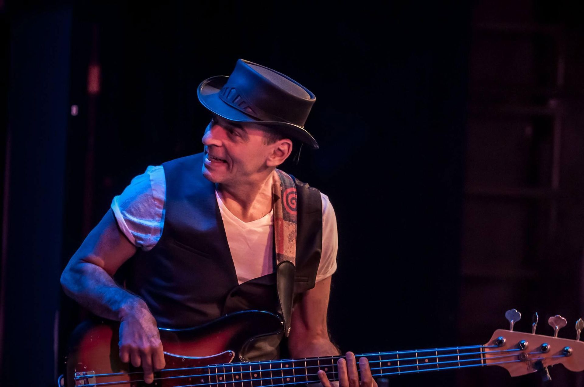 A man in a hat is playing a bass guitar on stage.
