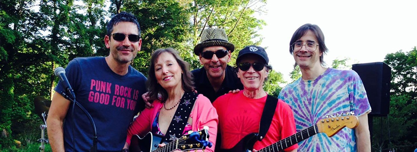 A group of people are posing for a picture while one of them is holding a guitar.