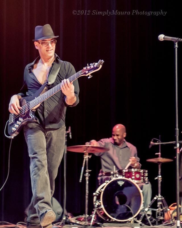 A man playing a guitar and a man playing drums on a stage