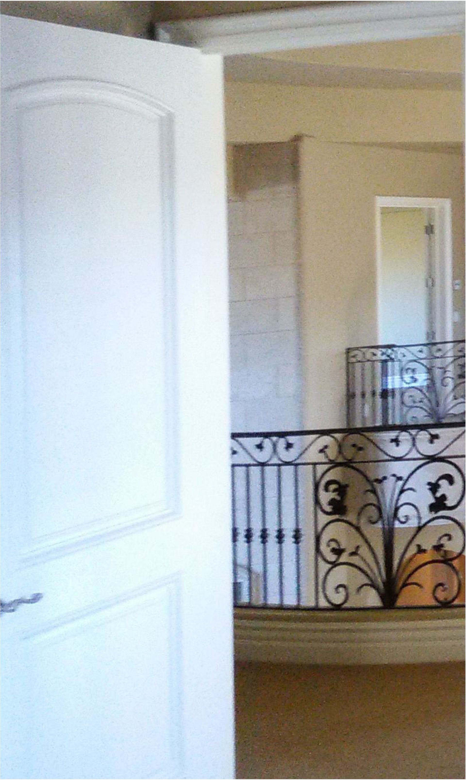 A white door is open to a balcony with a wrought iron railing