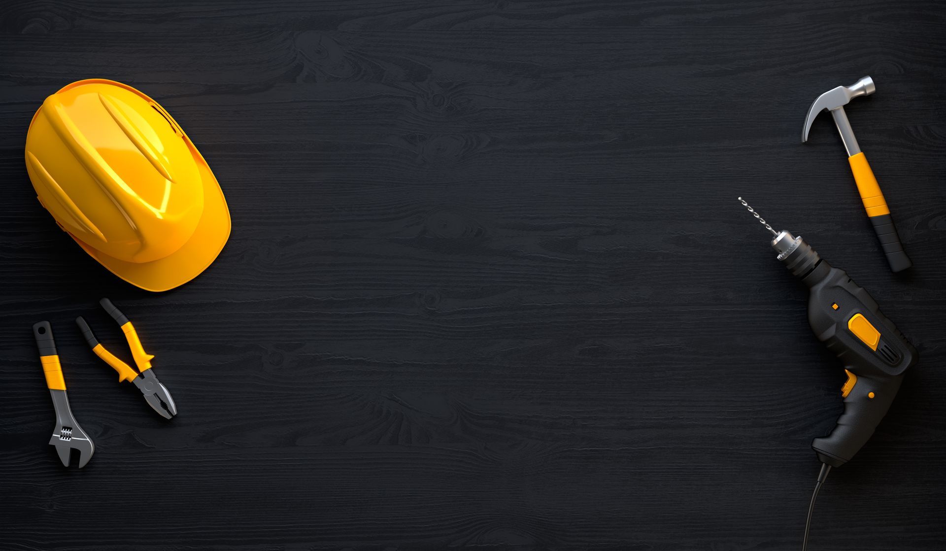 Un casque, une pince, un marteau, une perceuse et une clé sur une table en bois noir.