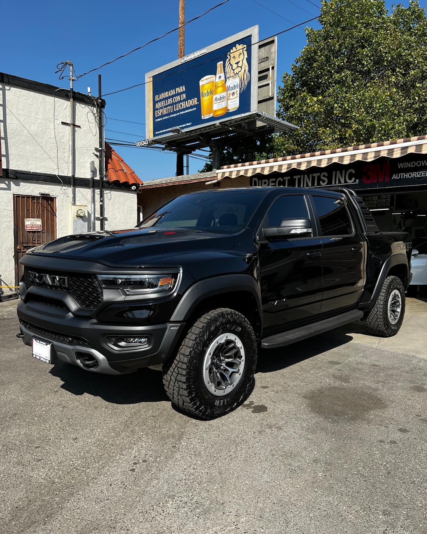 Black convertible car with white wall tires parked on the street; a man stands nearby.