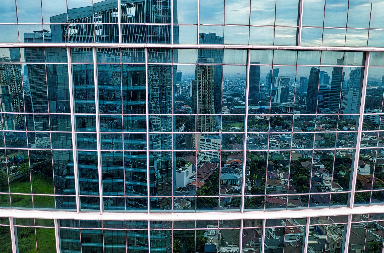 City skyline reflected in a grid of glass windows, creating a repeating view of buildings and sky.