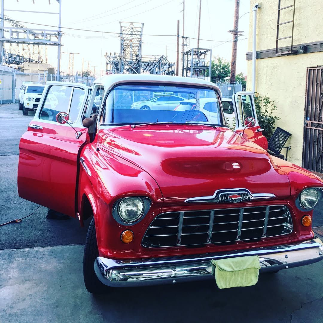 Red classic Chevrolet truck with open doors, parked outside.