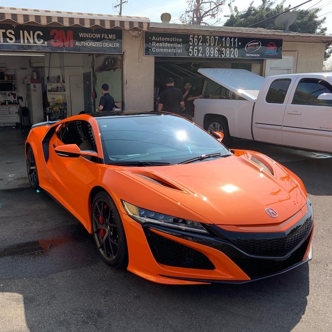 Orange Acura NSX sports car parked outside a shop.
