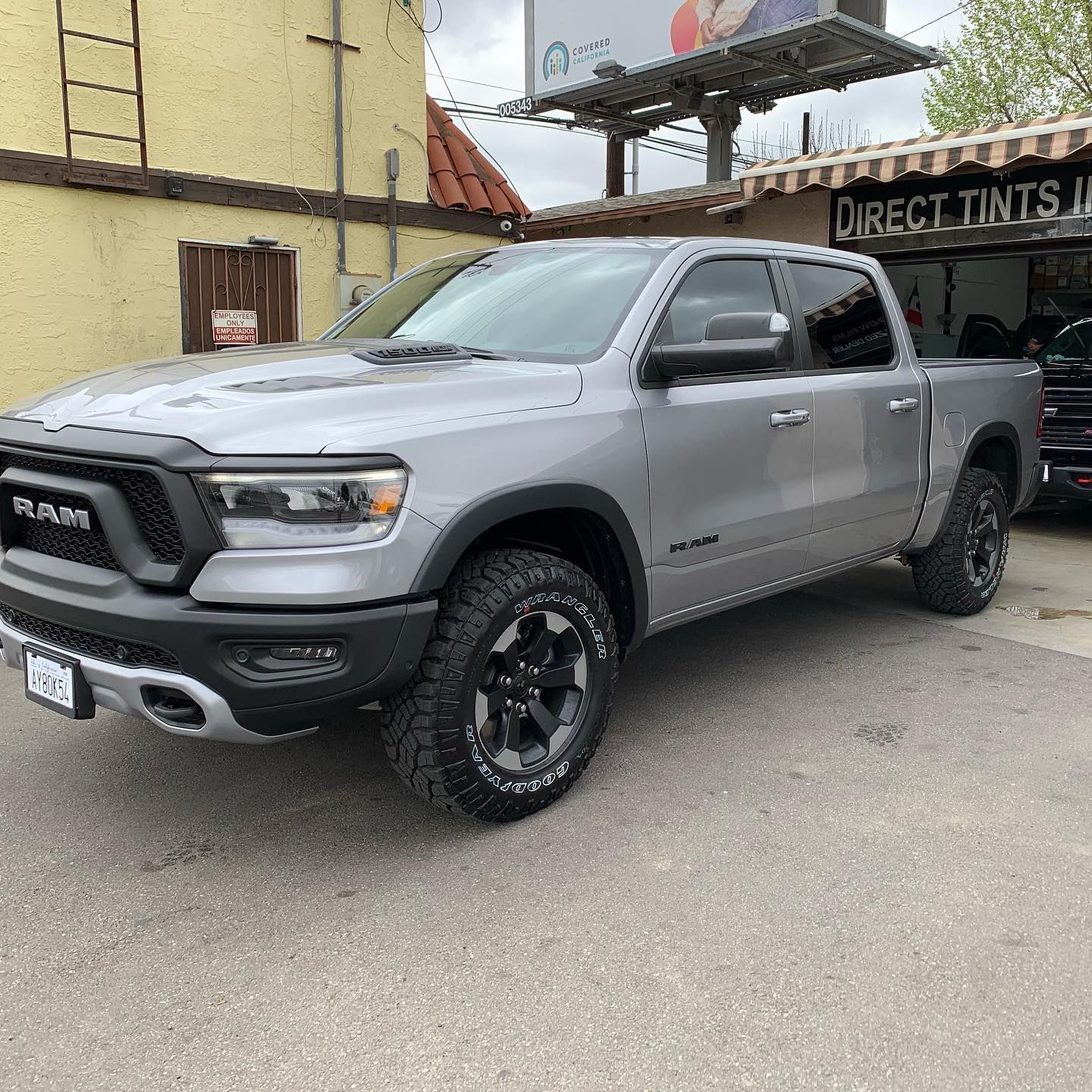 Silver Ram Rebel truck parked in front of a building with a tint shop sign.