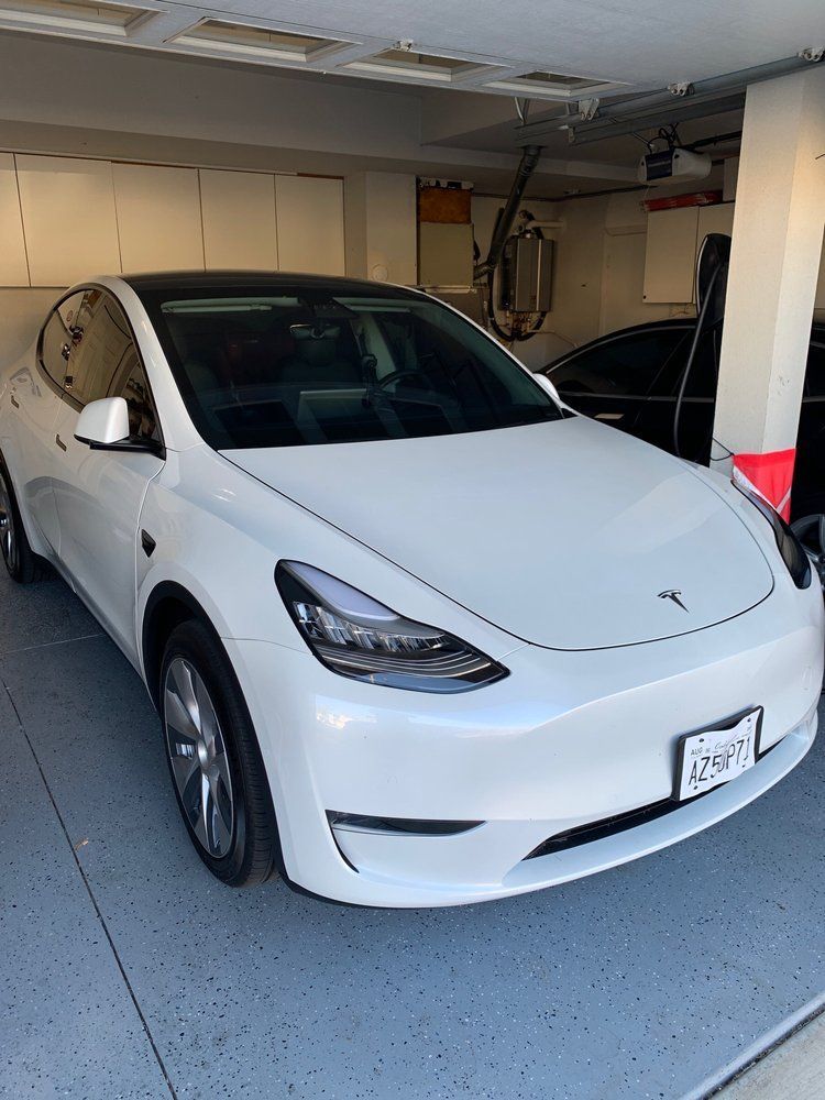 Glass-paneled building reflects blue sky and green trees.