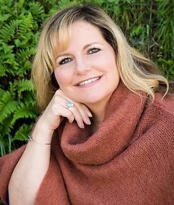 A woman wearing a turtleneck sweater and a ring is smiling for the camera.