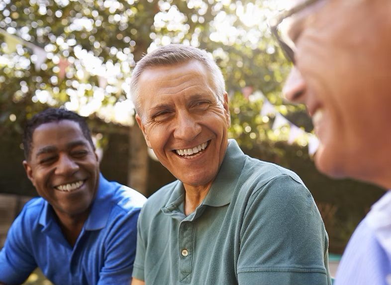Three men are sitting at a table talking and smiling.