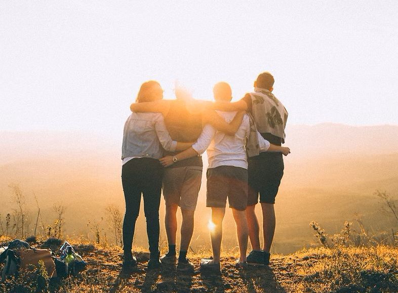 A group of people are hugging each other on top of a hill.