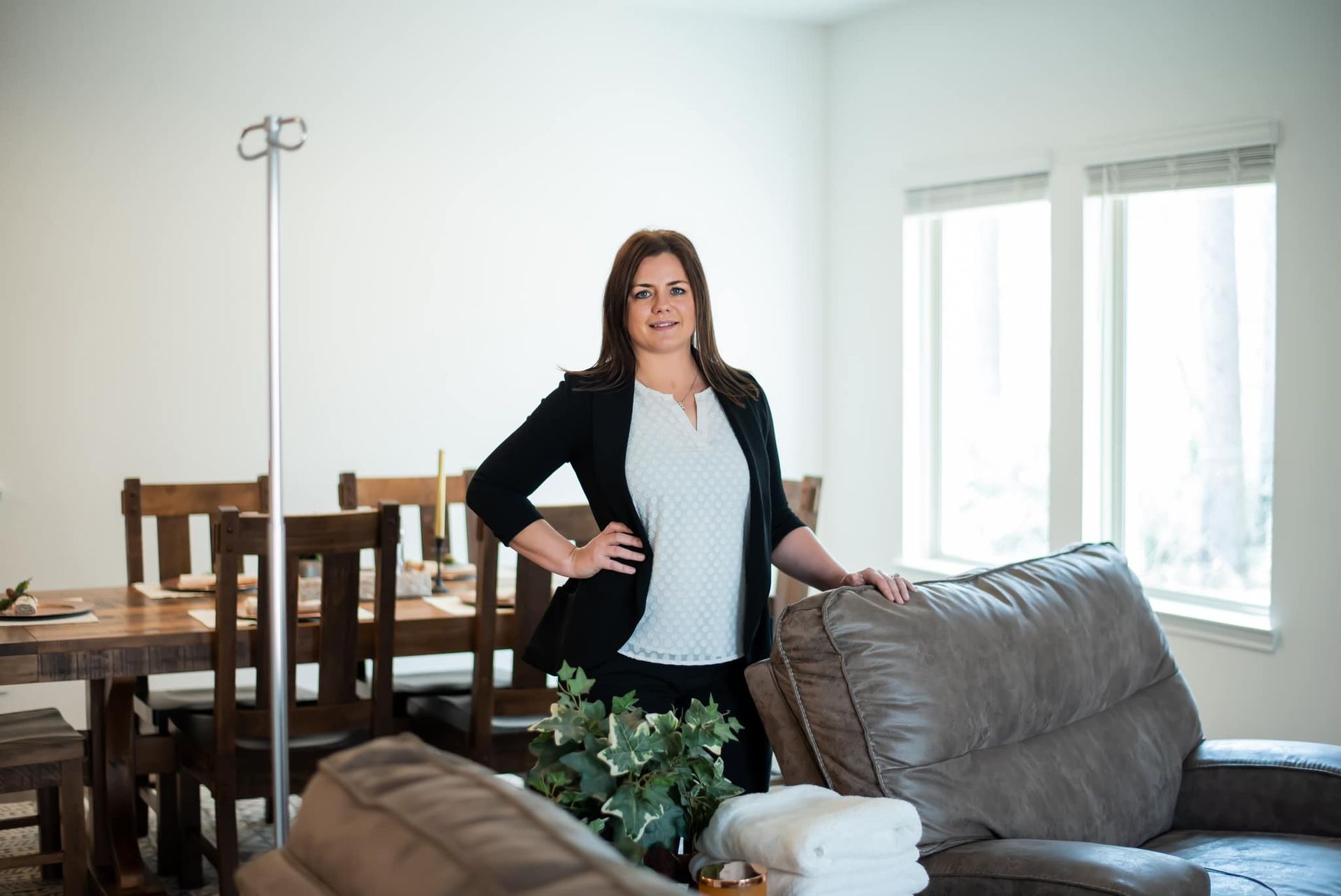 A woman in a black jacket and white shirt is leaning against a wall.