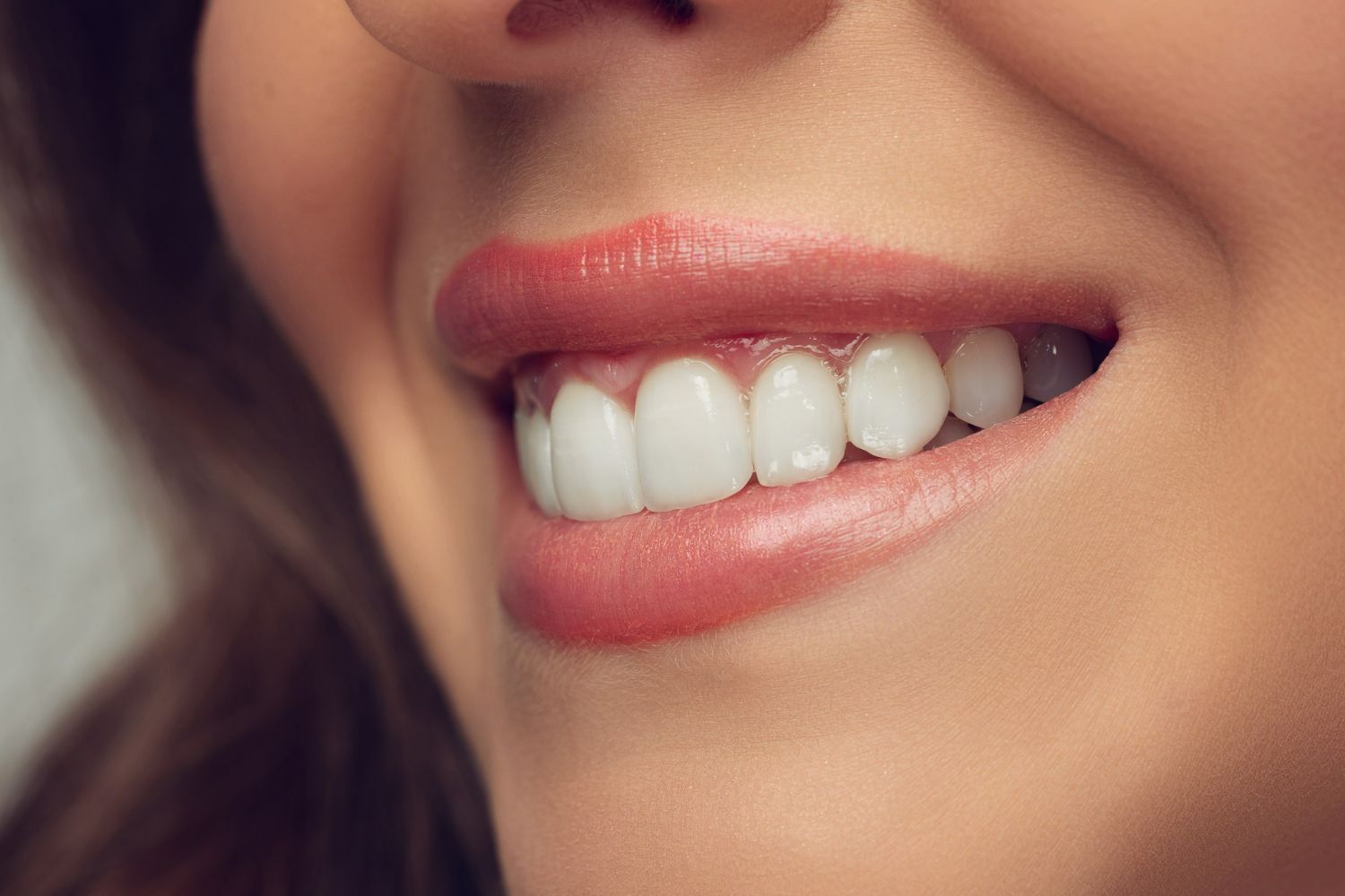 Close-up of a smiling mouth with pink lipstick and white teeth