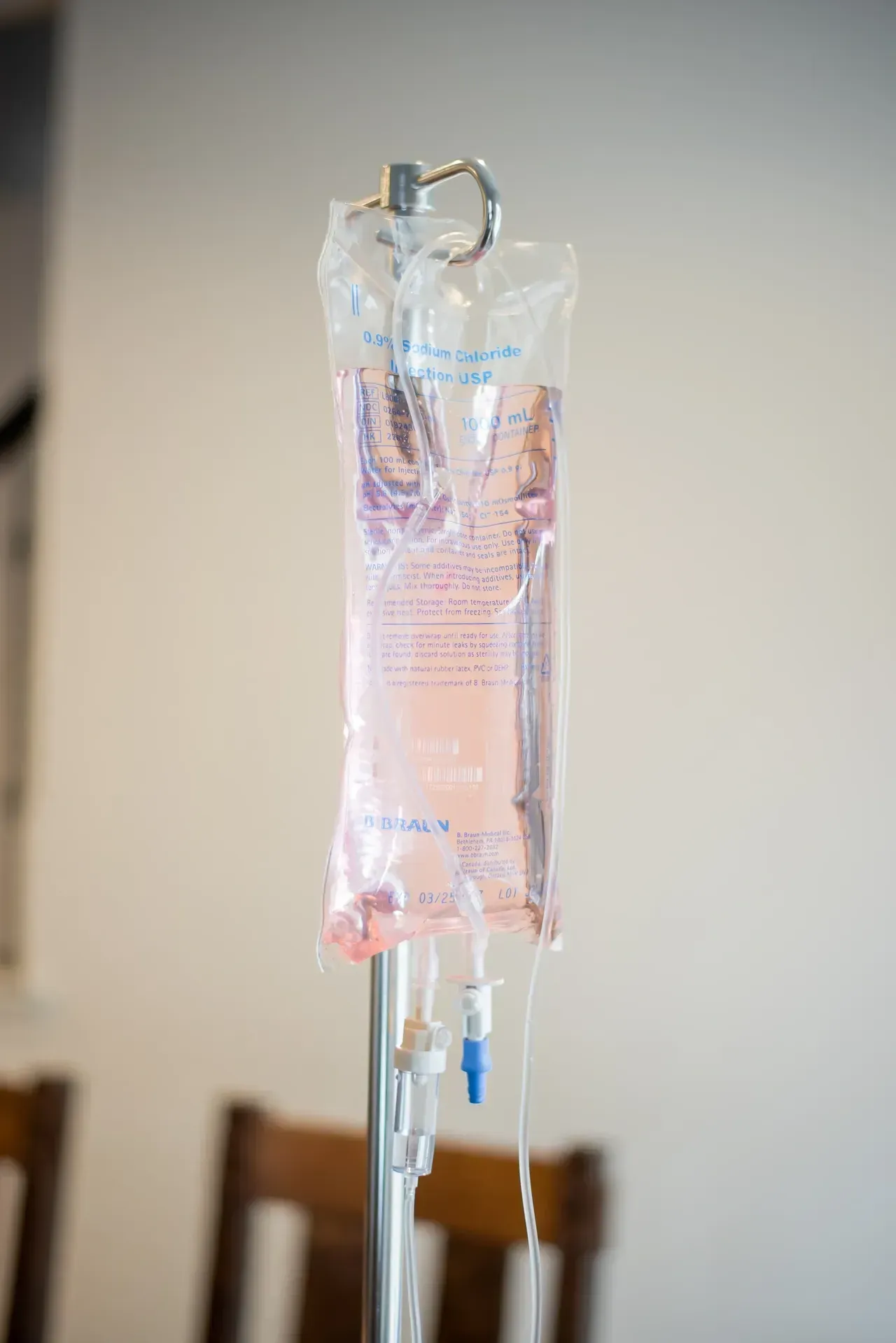 A bag of IV liquid is hanging from a pole in a hospital room.