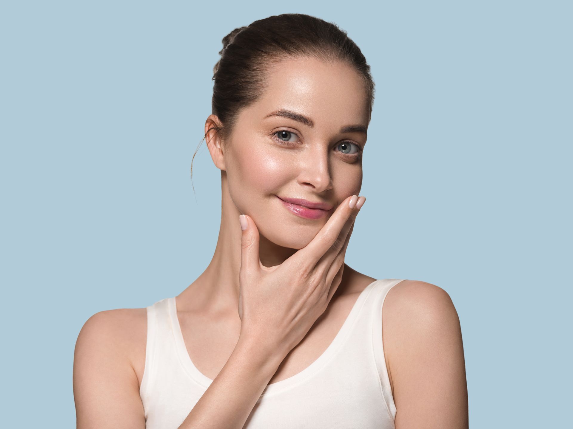 A woman is touching her face with her hand and smiling.