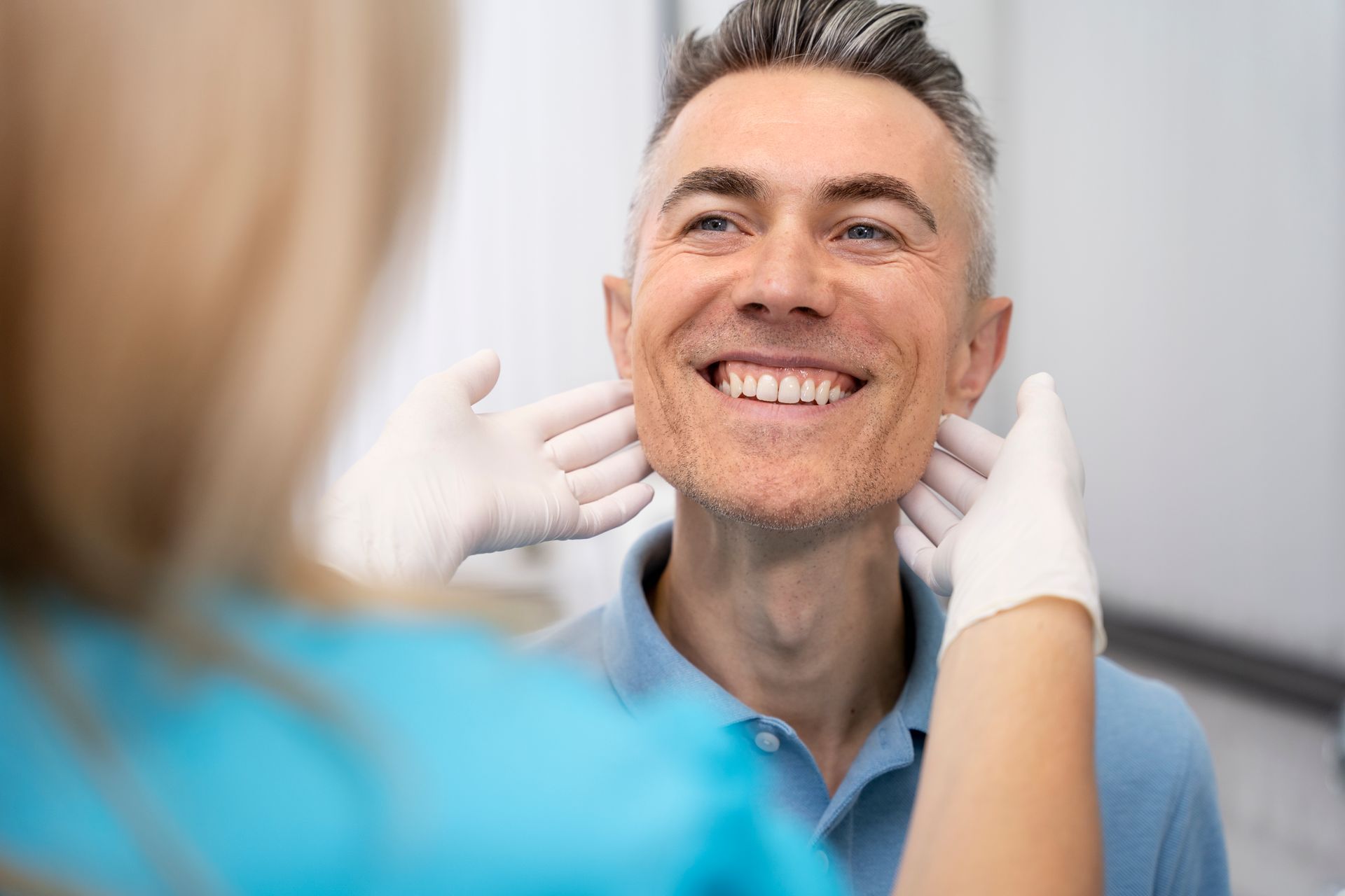 A man is smiling while being examined by a nurse.