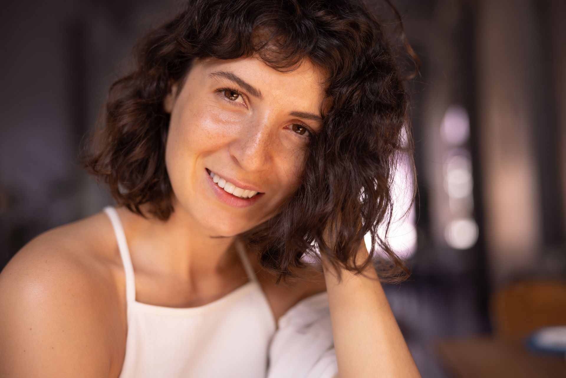 A woman with curly hair is smiling and looking at the camera.