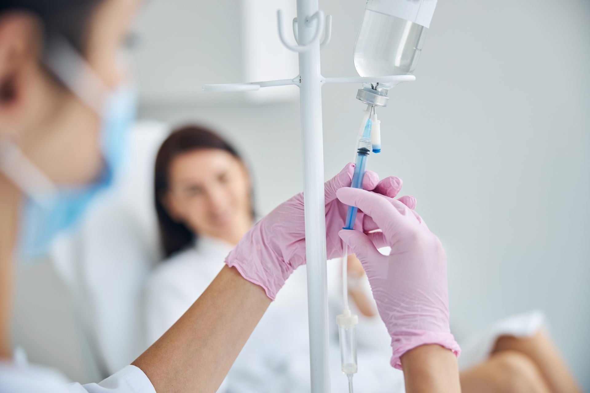 A doctor is preparing an IV hydration for a patient in a hospital bed.