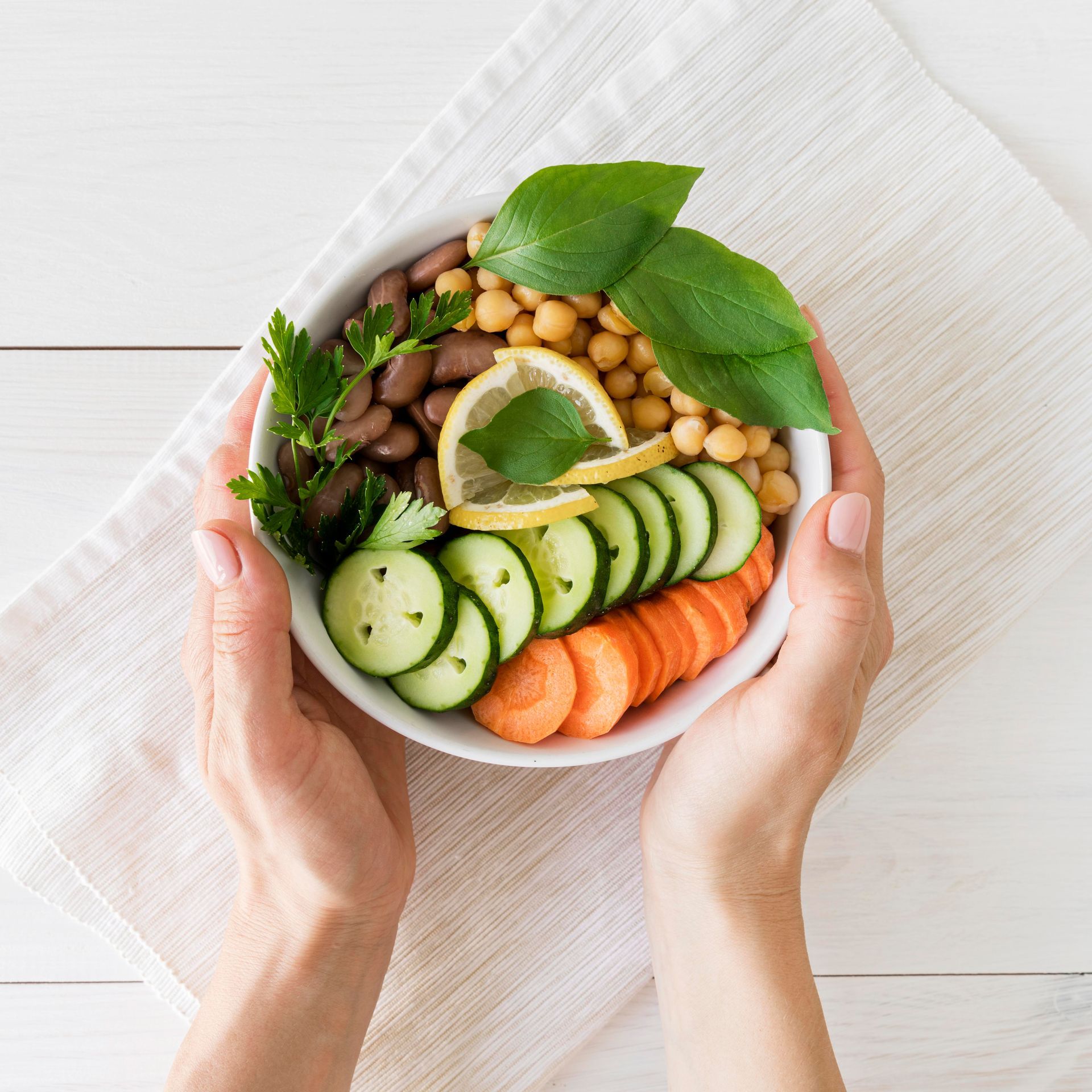A person is holding a bowl of vegetables and beans.