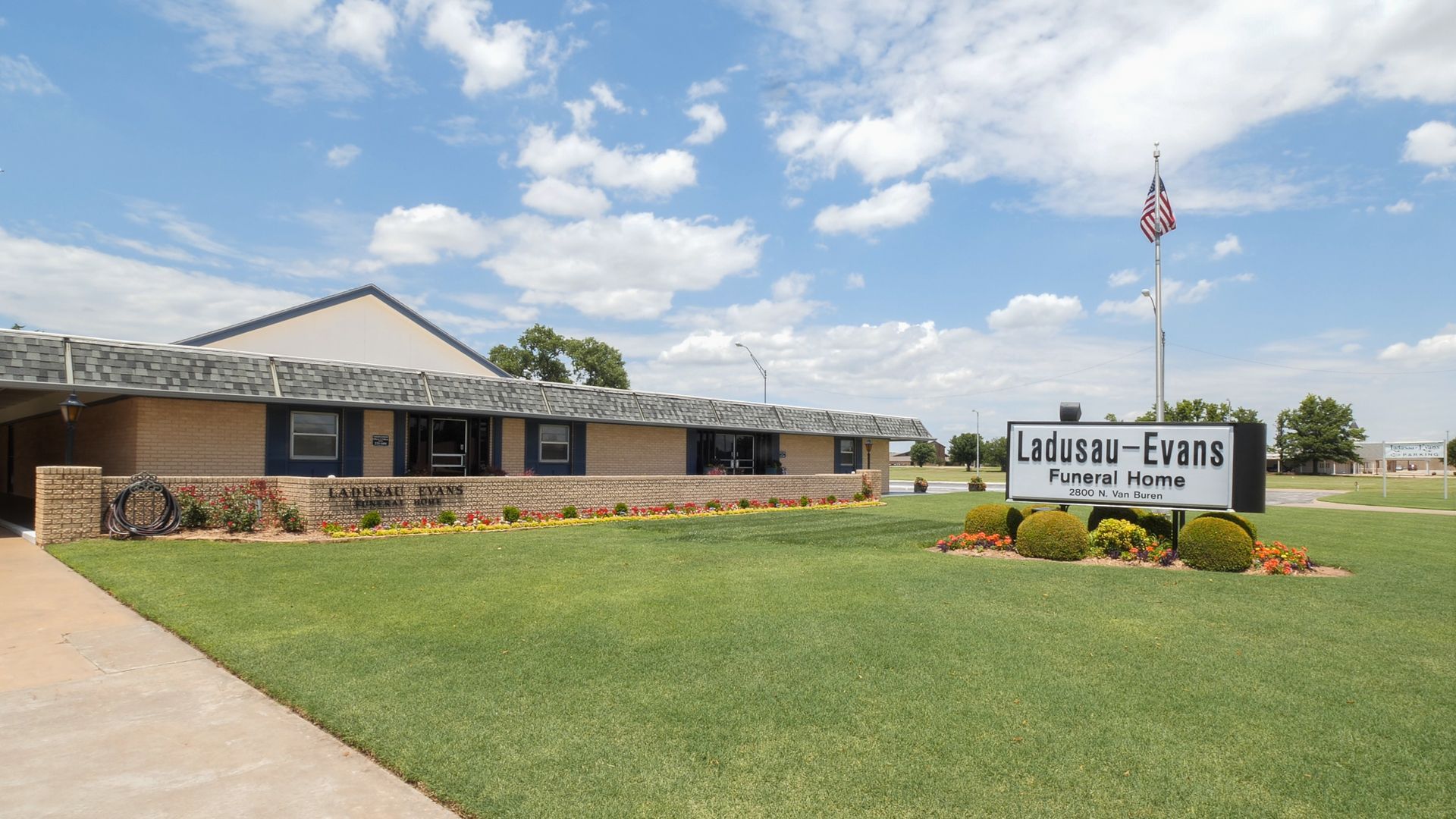 a wooden walkway leading to a gazebo overlooking a body of water at sunset .