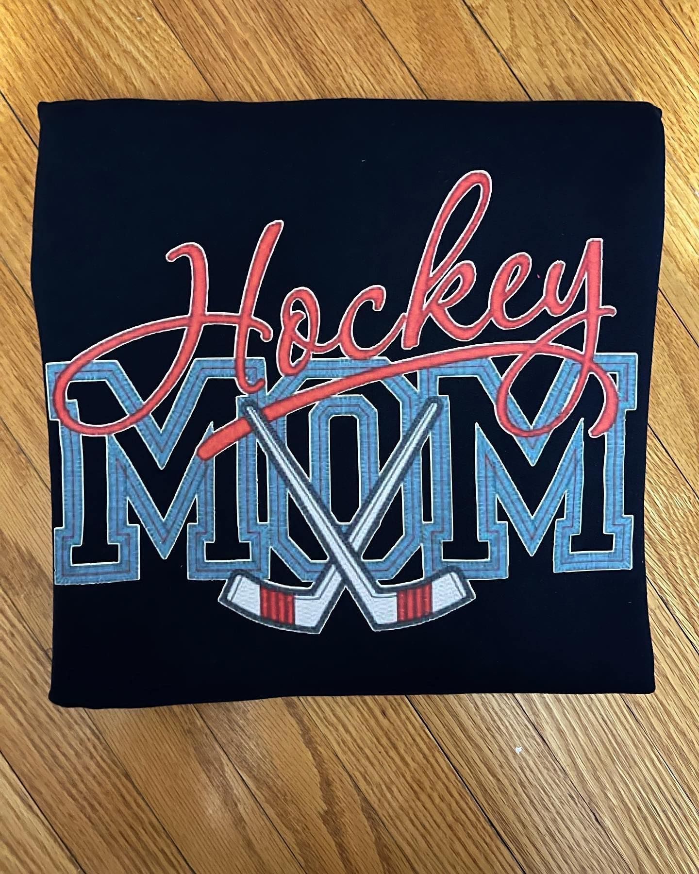 a hockey mom t-shirt is sitting on a wooden table .