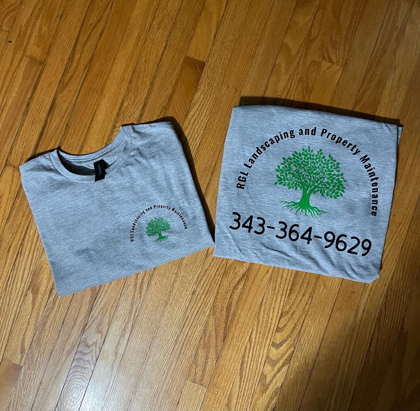 two t-shirts are sitting on a wooden floor .