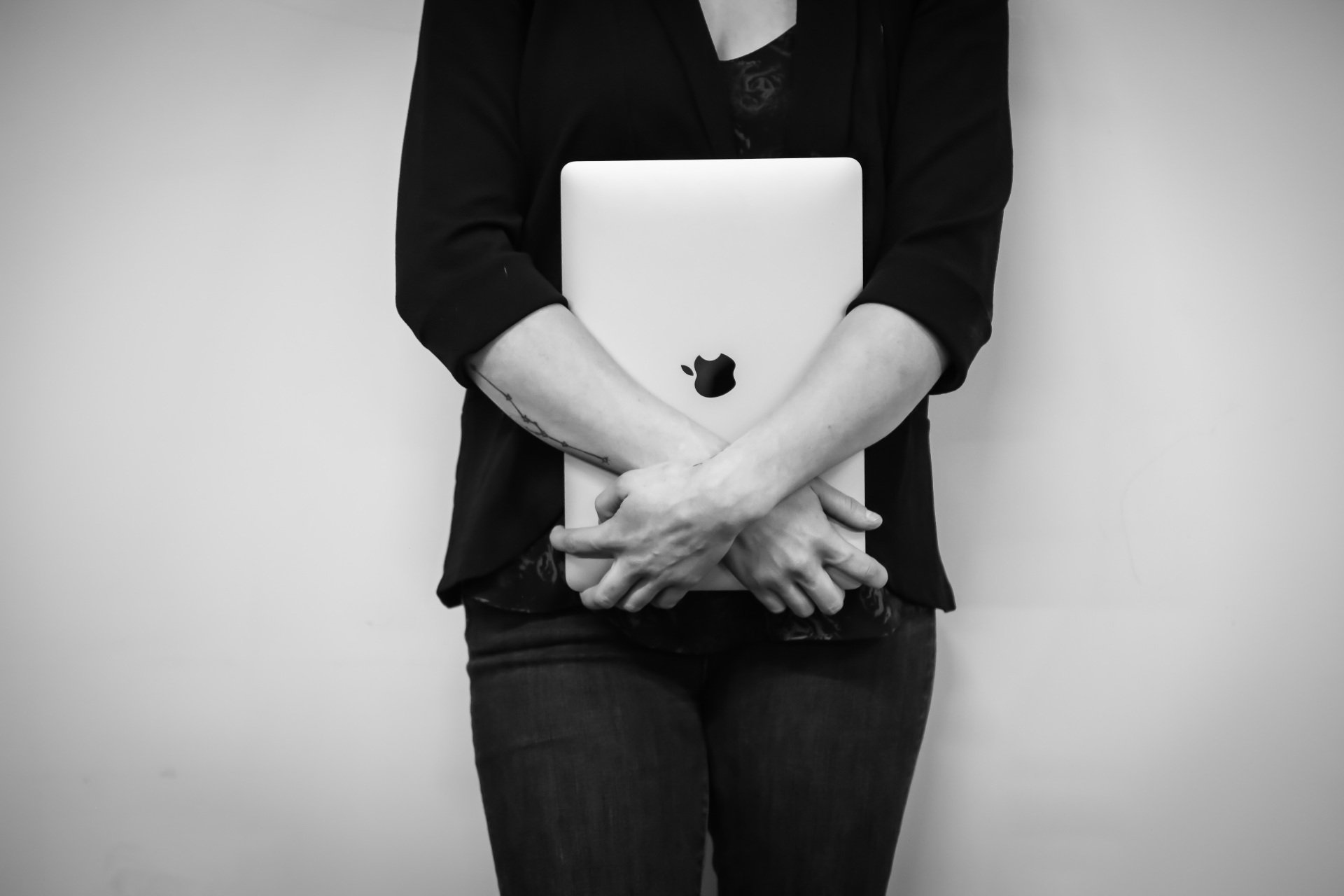 a black and white photo of a woman holding an apple laptop