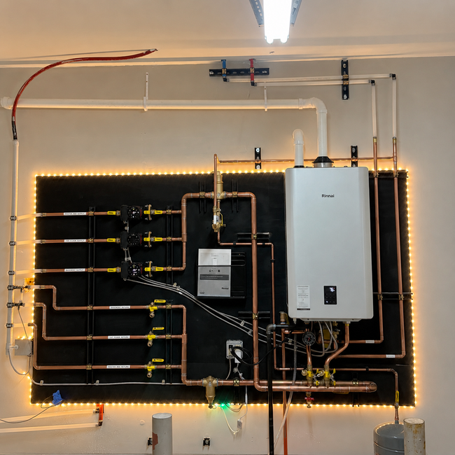 Wall-mounted utility panel with labeled pipes, valves, and a white boiler unit outlined by warm LED lights.
