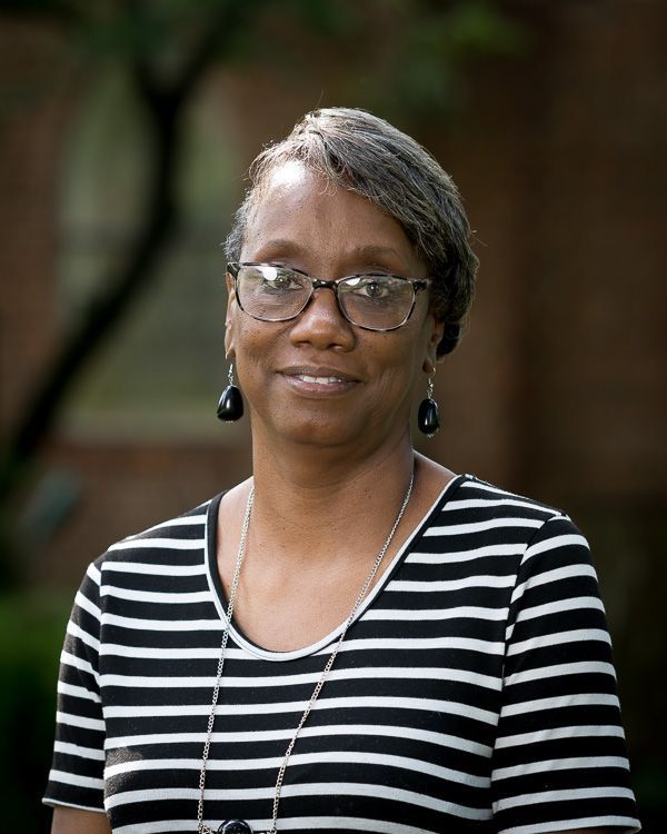 A woman wearing glasses and a striped shirt is smiling for the camera.