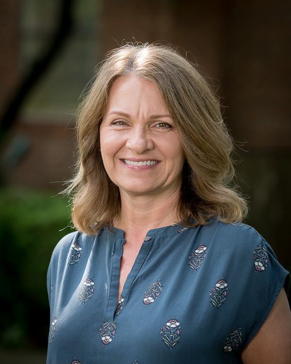 A woman in a blue shirt is smiling for the camera.