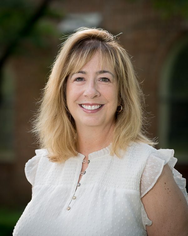 A woman in a white shirt is smiling for the camera.