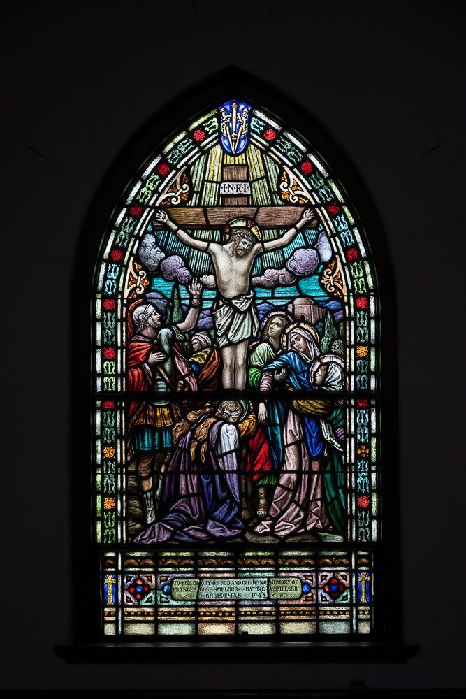 A stained glass window in a church shows jesus on the cross.
