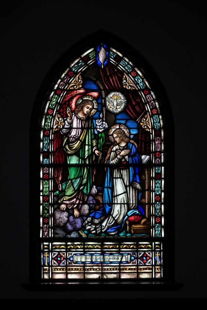 A stained glass window in a church shows a nativity scene.