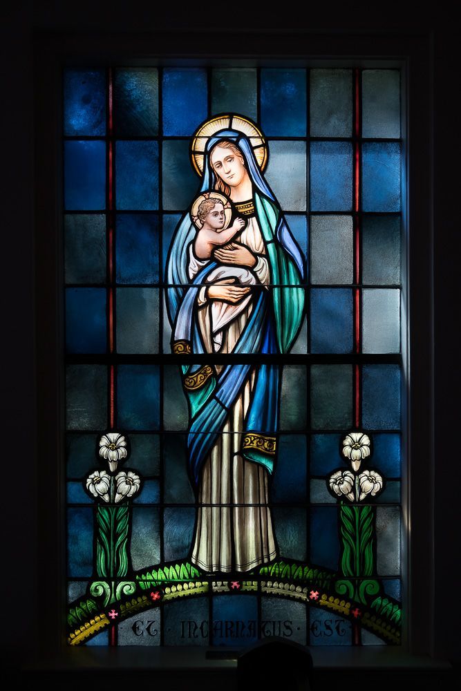 A stained glass window of a woman holding a baby
