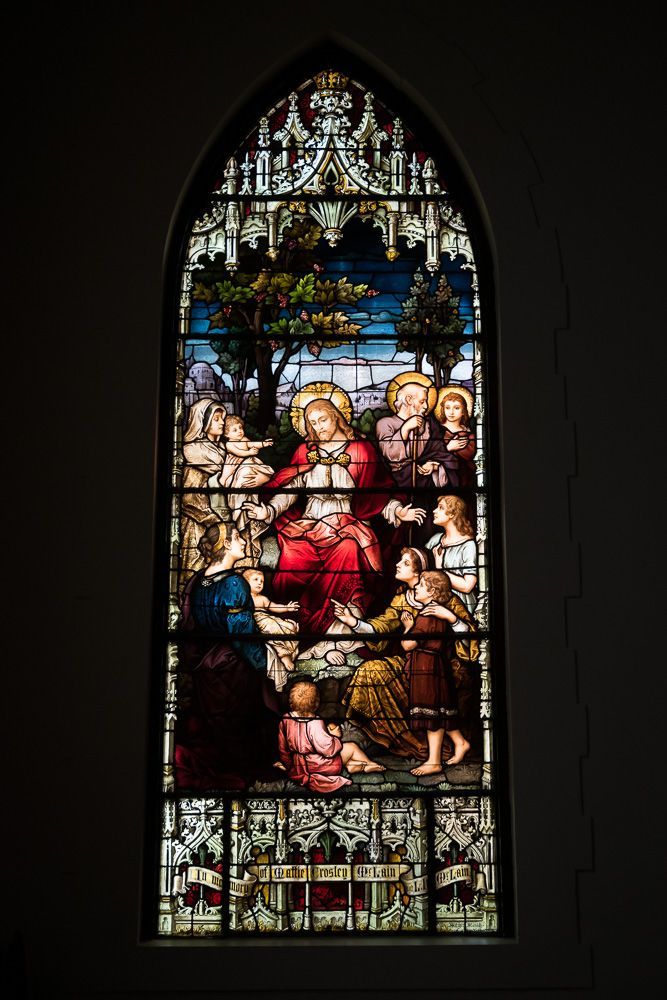 A stained glass window in a church depicting jesus surrounded by people.