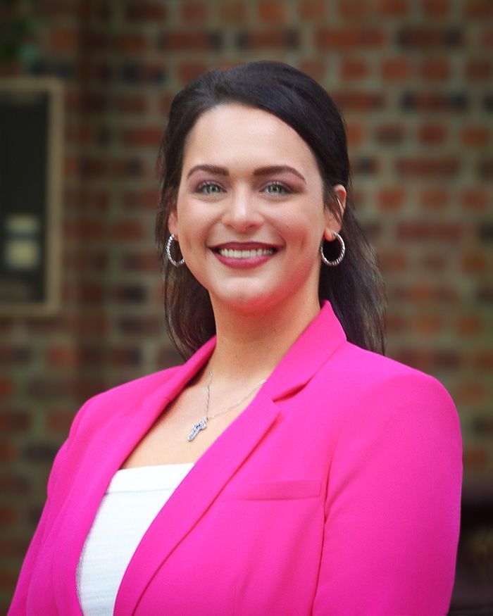 A woman in a green shirt and earrings is smiling for the camera.