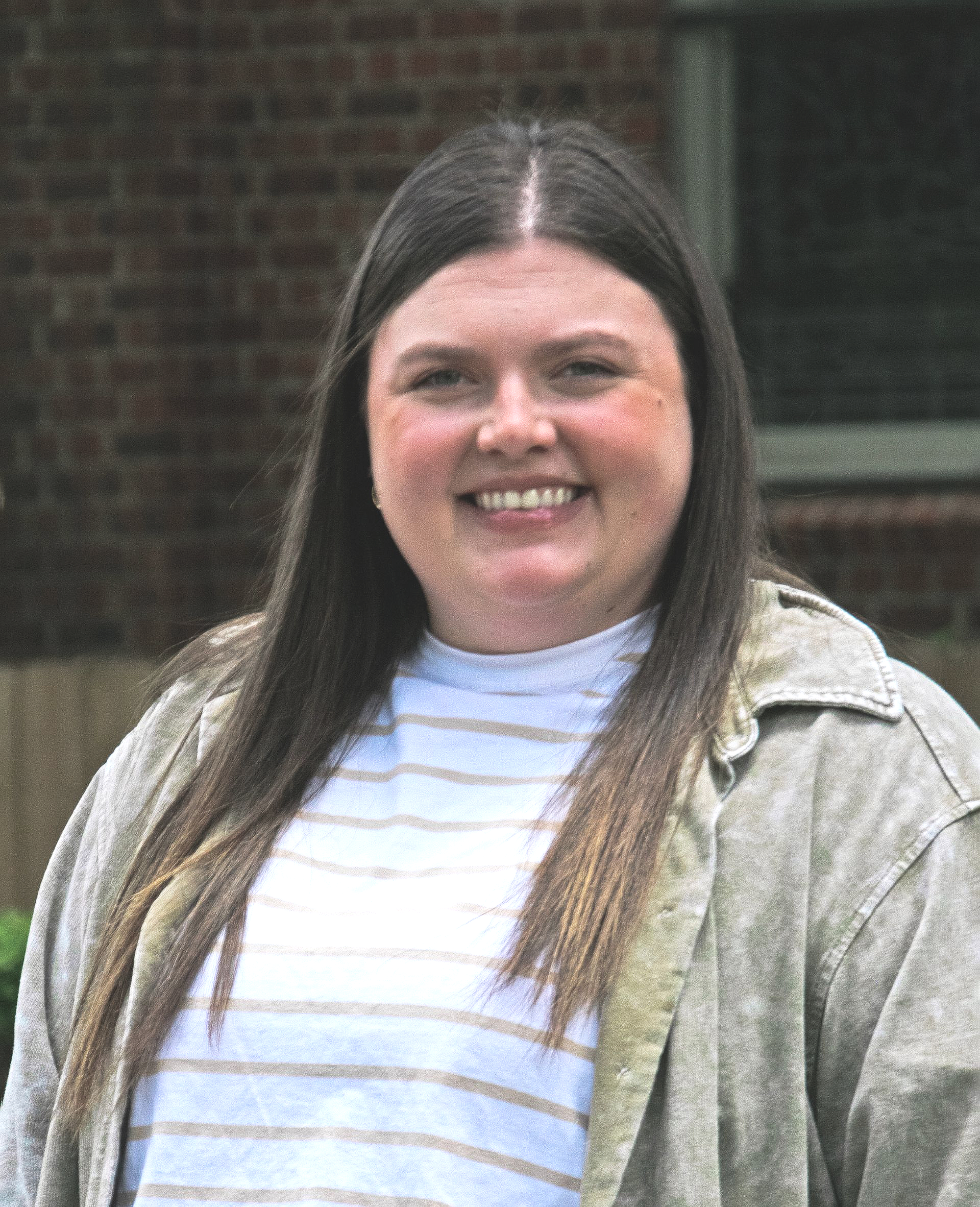 A woman wearing glasses and a striped shirt is smiling for the camera.