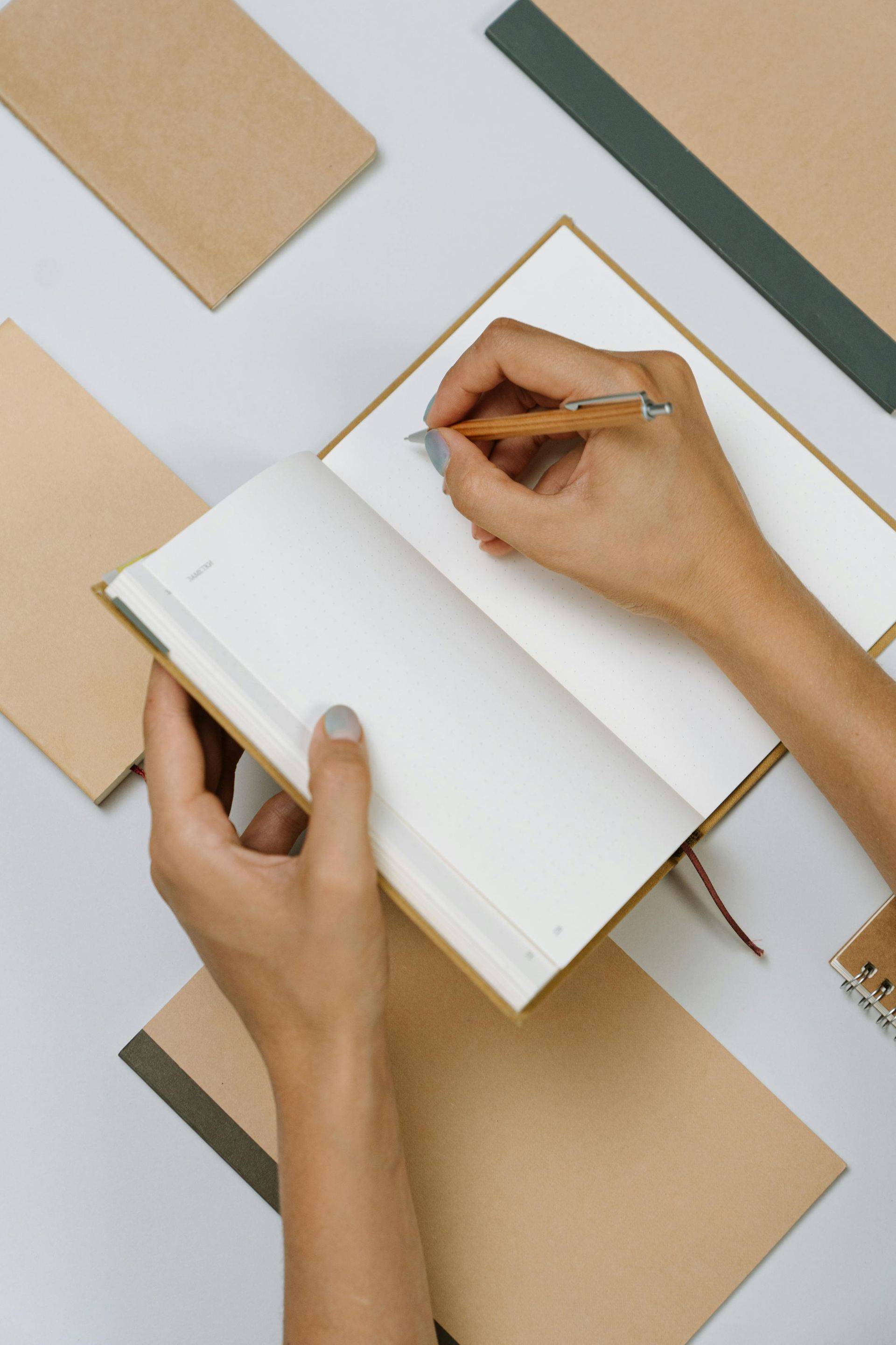 A person is writing in a notebook with a pen.