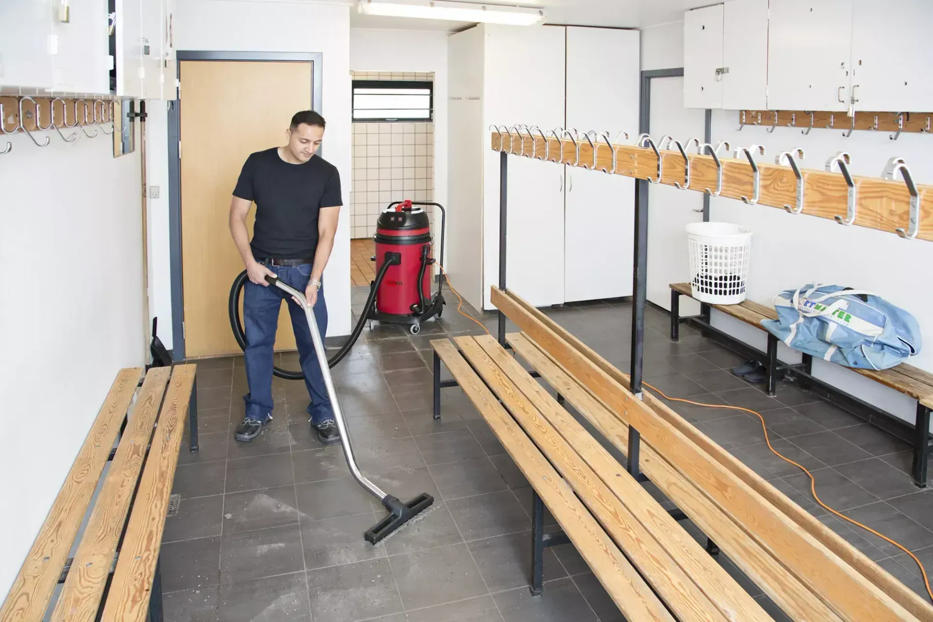 Silver and black industrial vacuum cleaner with red accents, on a wheeled base.