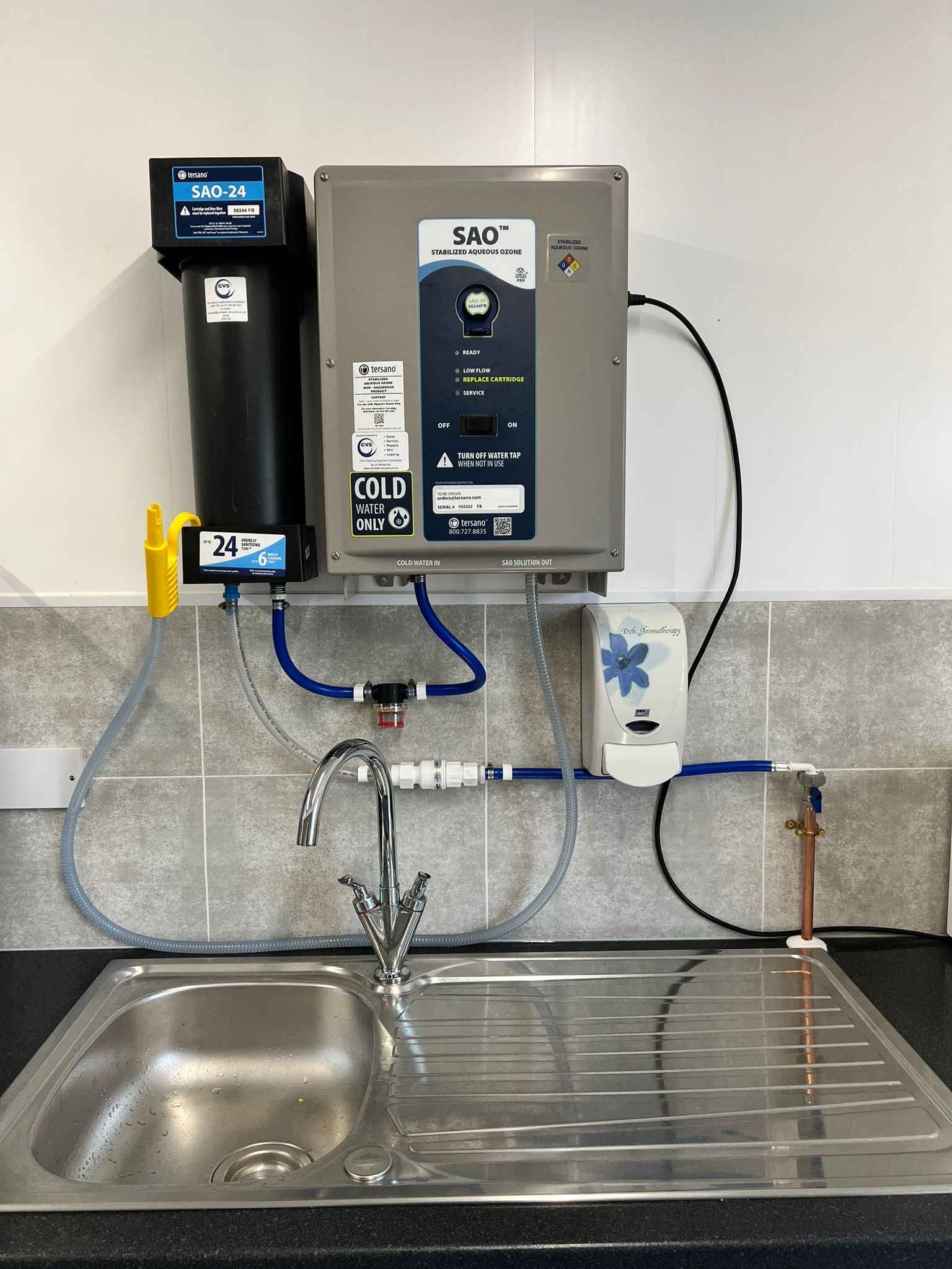 Water filtration system above a kitchen sink, with a faucet, and pipes.