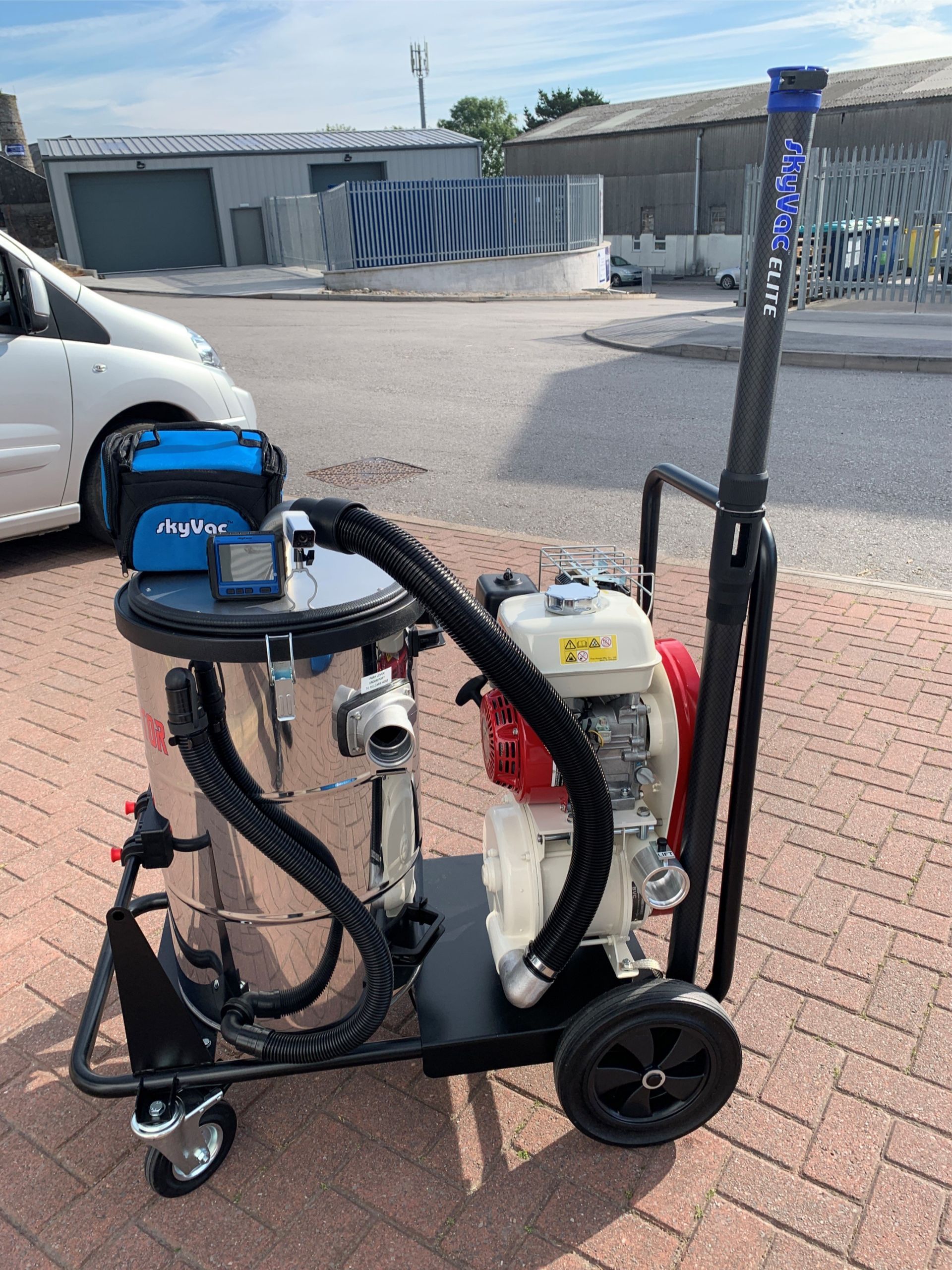 Industrial vacuum cleaner on wheels, with a Honda engine and blue handle, parked outside.